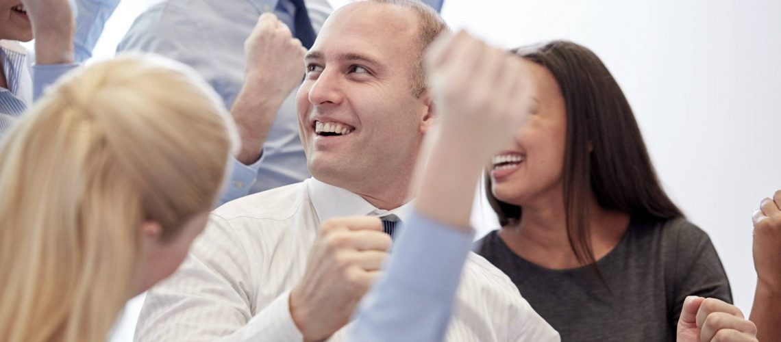 business, teamwork, people and success concept - smiling business team making triumph gesture in office